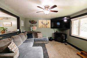 Living area with ceiling fan, carpet, and a textured ceiling