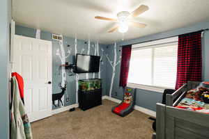 Bedroom featuring carpet floors, a textured ceiling, and ceiling fan