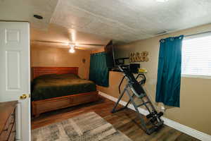 Bedroom with dark wood-type flooring, ceiling fan, and a textured ceiling