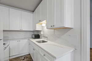 Kitchen with white cabinets, white electric range, light stone counters, and tasteful backsplash