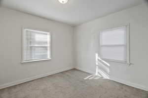Unfurnished room featuring light carpet and baseboards