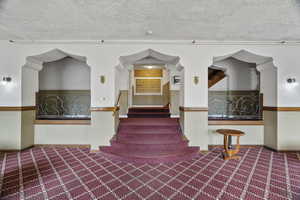 Stairs with carpet and a textured ceiling