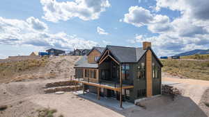 Rear view of house with a patio, roof with shingles, a chimney, and a mountain view