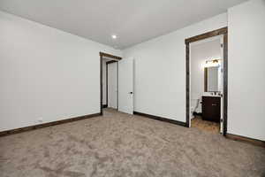 Unfurnished bedroom with light carpet, ensuite bath, and recessed lighting