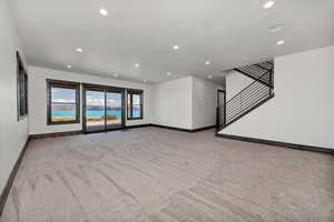 Unfurnished living room featuring light carpet and recessed lighting