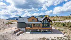 Rear view of house with a mountain view, a chimney, a sunroom, and a patio area