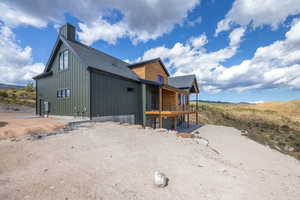 View of side of home with a shingled roof, a porch, and a mountain view