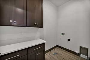 Laundry area with hookup for a washing machine, light wood-style floors, and cabinet space