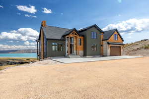 View of front of property with board and batten siding, driveway, stone siding, and a chimney