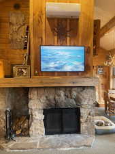 Detailed view of wooden walls, carpet, beam ceiling, and a stone fireplace