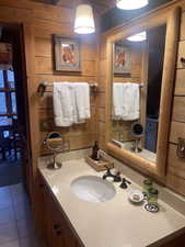 Bathroom with wooden walls, vanity, and tile patterned floors