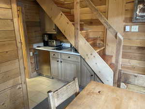 Bar area with wood walls, light tile patterned flooring, and stainless steel refrigerator