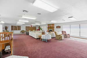 Carpeted living area featuring a textured ceiling and a fireplace