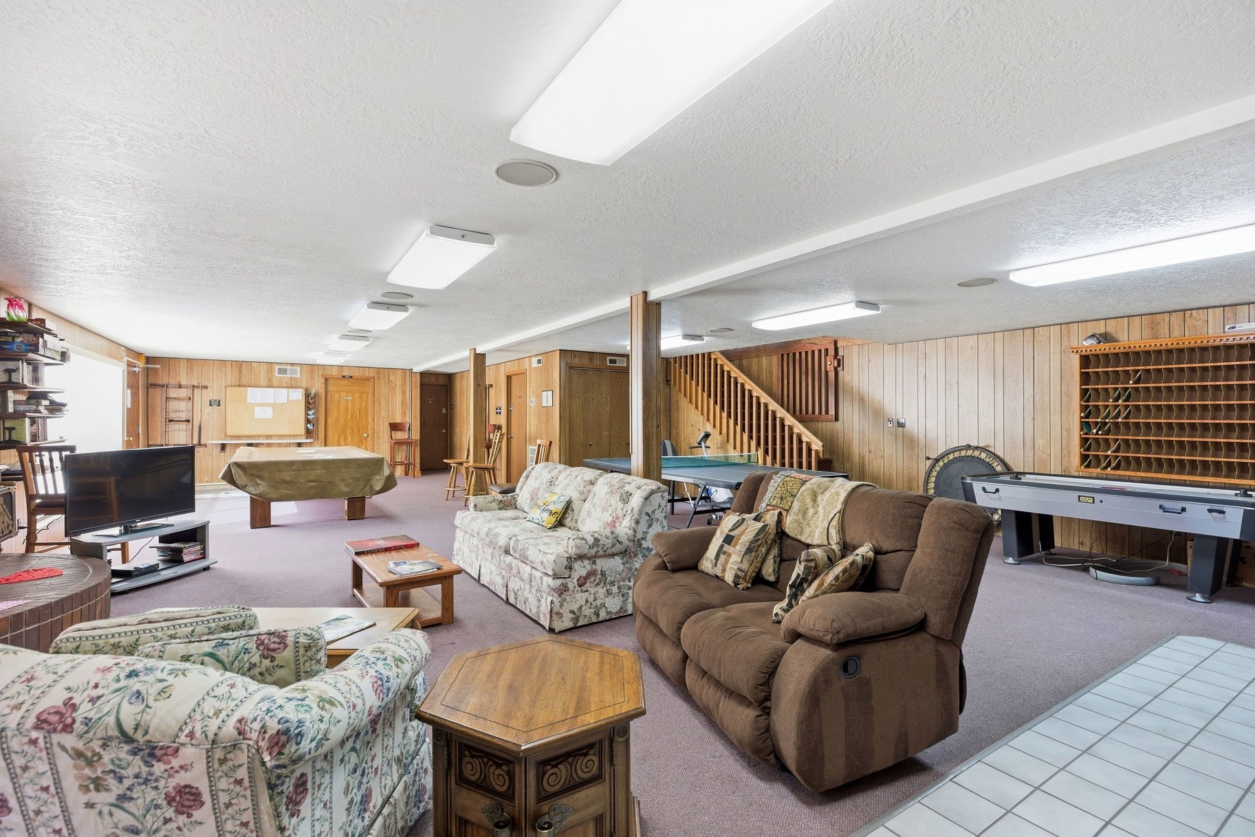 Living room with a textured ceiling, wood walls, pool table, and carpet flooring