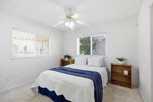 Bedroom with light colored carpet and a ceiling fan