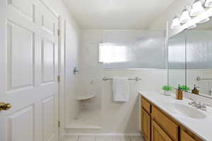 Bathroom with vanity, a marble finish shower, and light tile patterned floors