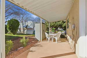 View of patio featuring outdoor dining space and a shed