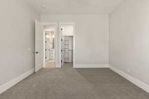 Unfurnished bedroom with light colored carpet and a walk in closet