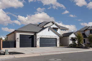 Modern farmhouse style home featuring concrete driveway, a garage, board and batten siding, and stone siding