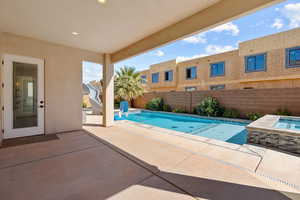 View of swimming pool with patio surround, an in-ground hot tub, a fenced backyard, and a water slide