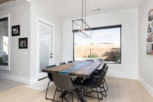 Dining room with light wood-style floors and suspended lighting
