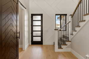 Foyer entrance with light wood finished floors and a barn door