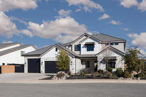 Modern inspired farmhouse with board and batten siding, stone siding, concrete driveway, and a garage