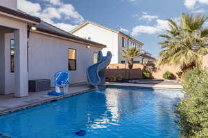 View of pool with a water slide and patio surround