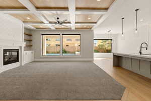 Unfurnished living room featuring coffered ceiling, healthy amount of natural light, recessed lighting, a fireplace, and light wood-style floors
