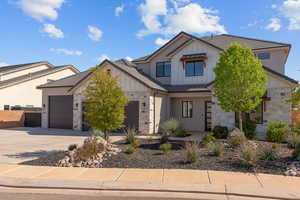 Modern farmhouse style home with board and batten siding, stone siding, driveway, an attached garage, and a tile roof