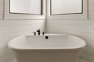 Full bath with a freestanding tub and wood walls