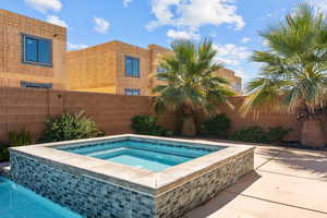 View of pool featuring an in-ground hot tub, patio surround, and a fenced backyard