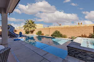 View of pool featuring a water slide, patio surround, and a fenced backyard