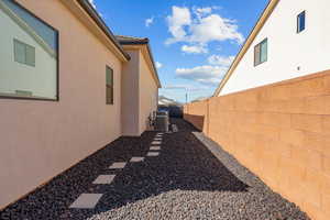 View of side of property with a fenced backyard, stucco siding, and a tile roof