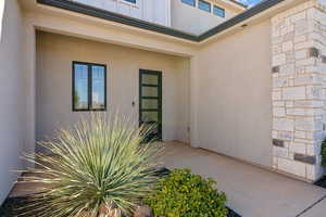 View of exterior entry with stone siding and stucco siding