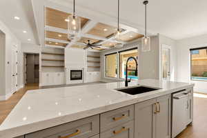 Kitchen with light wood-style flooring, light stone counters, coffered ceiling, plenty of natural light, and a fireplace