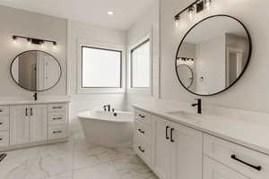 Full bath featuring a freestanding bath, two vanities, light marble finish floors, and recessed lighting