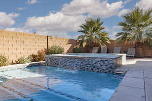 Combined pool / hot tub with a fenced backyard and a patio area