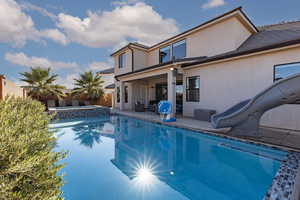 Integrated pool / spa with a water slide, a patio area, and a fenced backyard