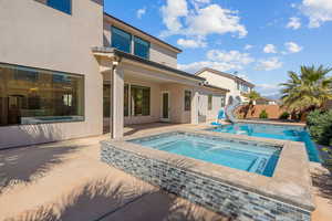 Swimming pool with an in-ground hot tub, a water slide, a patio, and a fenced backyard