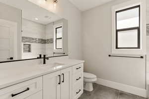 Bathroom featuring vanity, tiled shower, and dark tile patterned floors