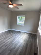 Unfurnished room with dark wood-style flooring, a ceiling fan, and a textured ceiling
