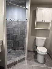 Full bath featuring tiled shower, dark tile patterned floors, and vanity