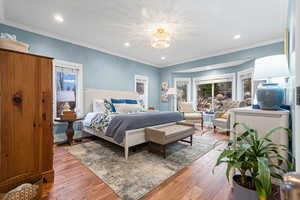 Primary Bedroom with hardwood / wood-style floors, ornamental molding, and a chandelier