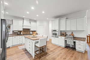Kitchen featuring a kitchen breakfast bar, a center island, white cabinets, recessed lighting, and stainless steel appliances