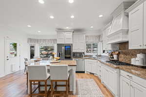 Kitchen with white cabinetry, a breakfast bar area, backsplash, light wood finished floors, and crown molding