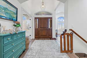 Entrance foyer with dark wood finished floors, vaulted ceiling, and arched walkways