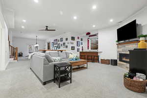 Living area with a ceiling fan, a tile fireplace, recessed lighting, and ornamental molding