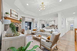 Living area featuring light wood finished floors, a fireplace, a chandelier, and crown molding