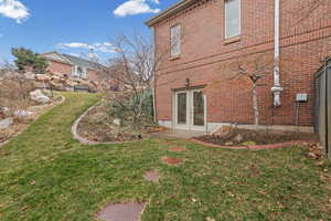 View of side of property with a yard, french doors, and brick siding, walk-out basement